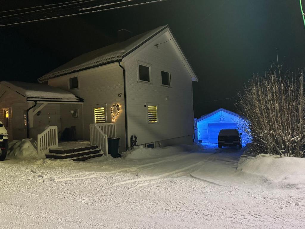 una casa con una luz azul en la nieve por la noche en Kirkegårdsveie 62, 