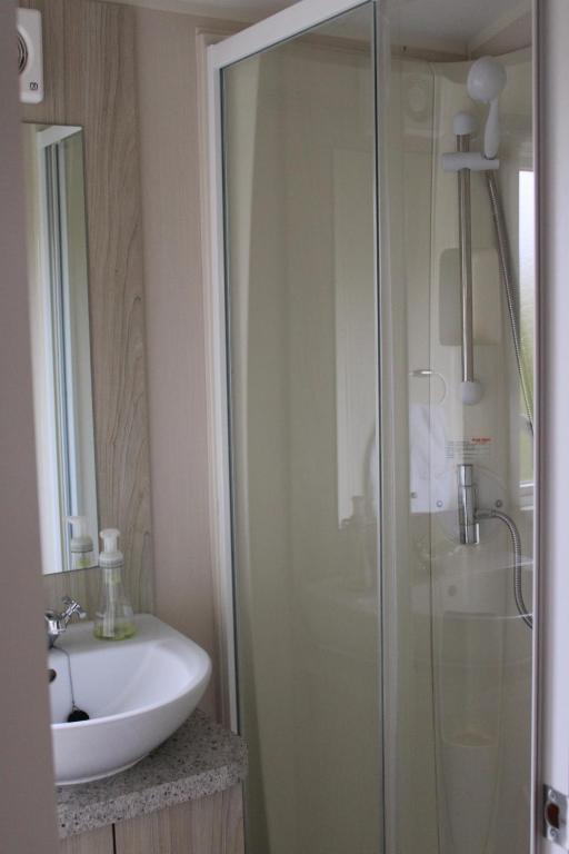 uma casa de banho com uma cabina de duche em vidro e um lavatório. em Cosy beachfront getaway in Mersea em West Mersea