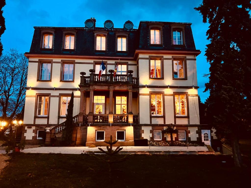 une grande maison éclairée la nuit dans l'établissement Hôtel Le Manoir, à Barr