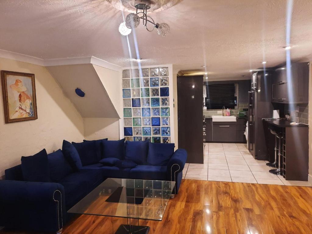 a living room with a blue couch and a glass table at Home Away in a Close in Thamesmead