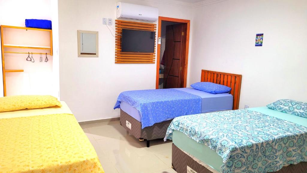 a room with two beds and a television in it at Praieira Hostel&Pousada in Itacaré