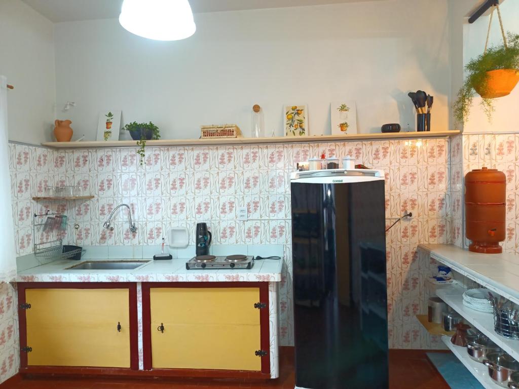 a kitchen with a black refrigerator in a room at É Hostel - Guesthouse in Ouro Preto