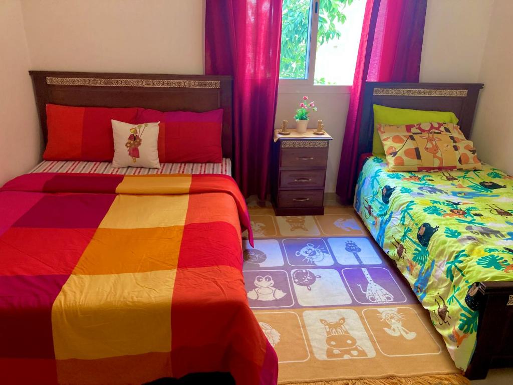 Appartement beau et familial connecté في طنجة: غرفة نوم ملونة مع سريرين ونافذة