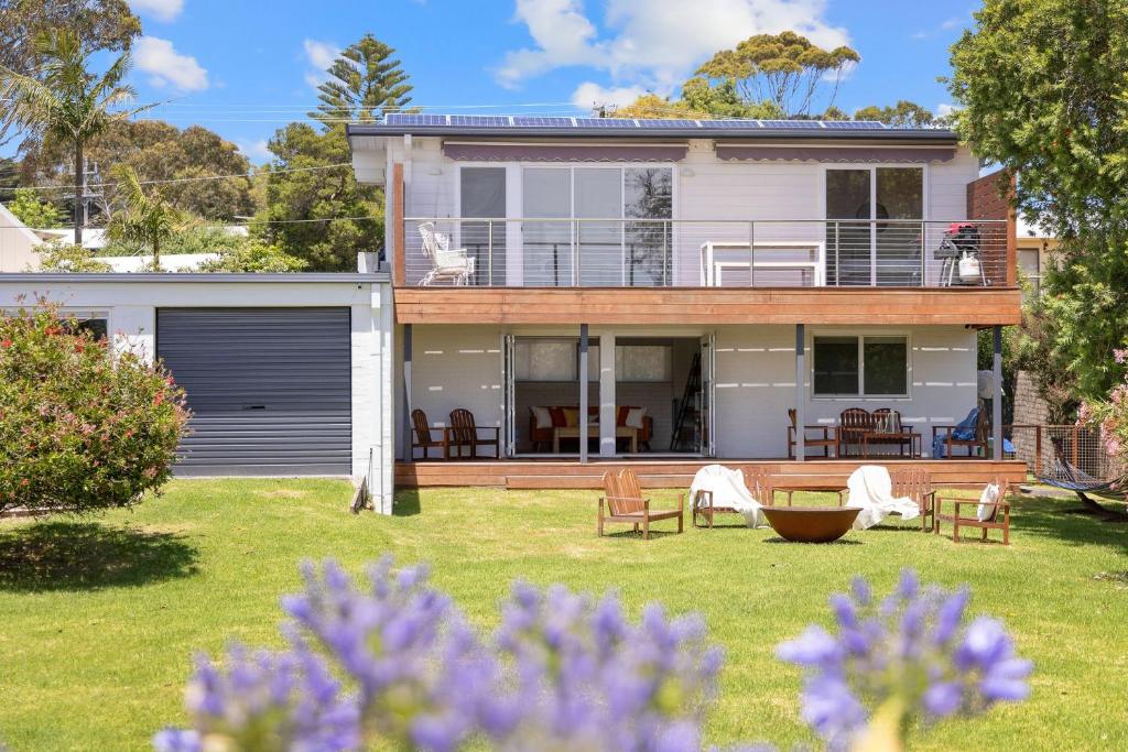 a house with a deck and a yard with purple flowers at Casa Blu in Cowes
