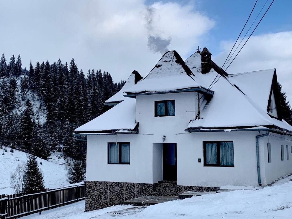 uma casa branca com neve no telhado em Pensiunea Valea Dorului em Fundstica