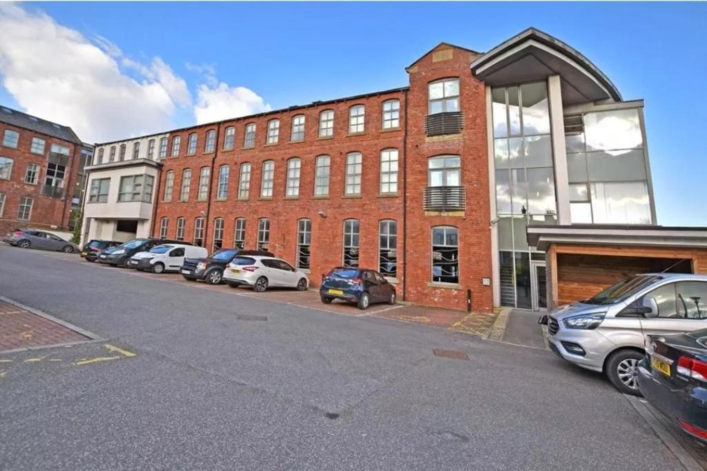 a large brick building with cars parked in a parking lot at Homestay by BIC Melbourne 14 - LEEDS in Morley