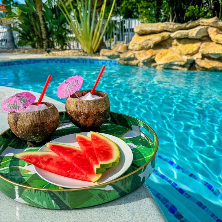 a plate of watermelon and fruit on a tray next to a pool at Captain's Quarters Marathon in Marathon