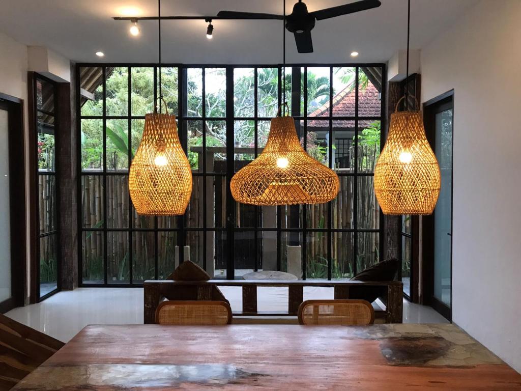 ein Esszimmer mit drei Lichtern, die von der Decke hängen in der Unterkunft De, dalam secret nature in Ubud