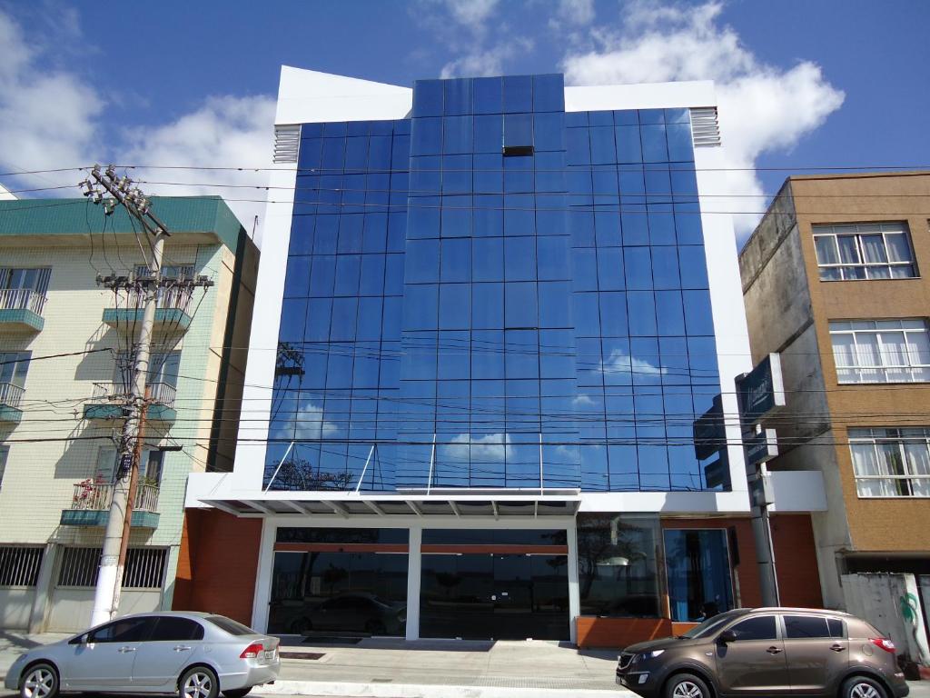 two cars parked in front of a glass building at Hotel Minuano in Vitória