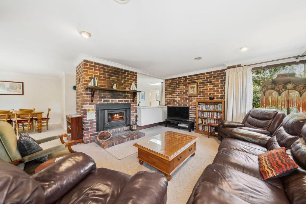 a living room with leather furniture and a fireplace at Rosella Retreat in Blackheath