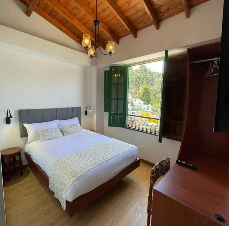 ein Schlafzimmer mit einem großen Bett und einem Fenster in der Unterkunft VILLA DE MOYA HOTEL MONGUI in Monguí
