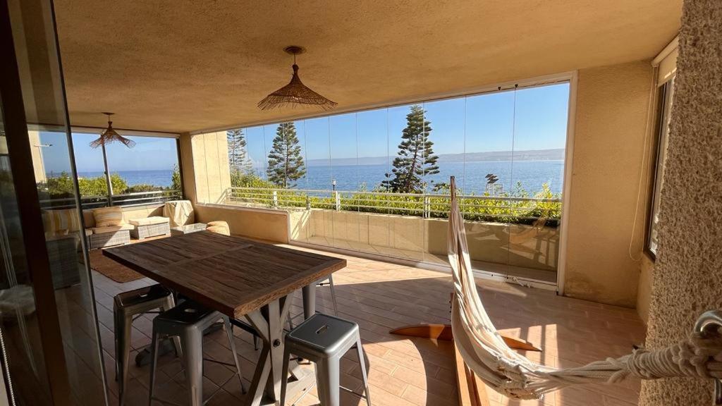 a balcony with a table and chairs and a view of the ocean at Depto de lujo en Punta Fraile, frente mar, 140 m2, amplias areas verdes, piscina, hamaca, tranquilidad in Algarrobo