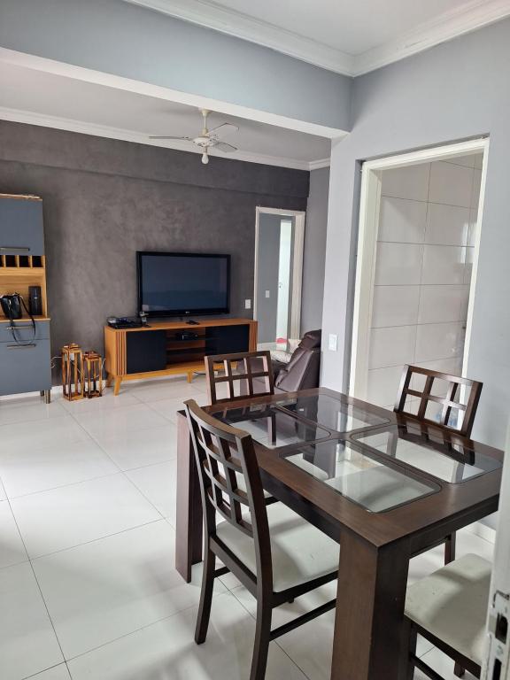 a living room with a table and chairs and a television at Cobertura Guarujá in Guarujá