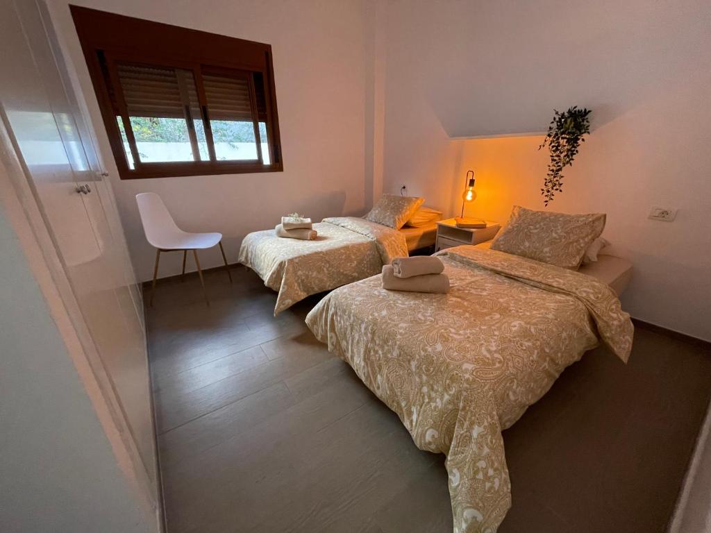 a bedroom with two beds and a chair and a window at Apartamento RODA - Candelaria in Candelaria