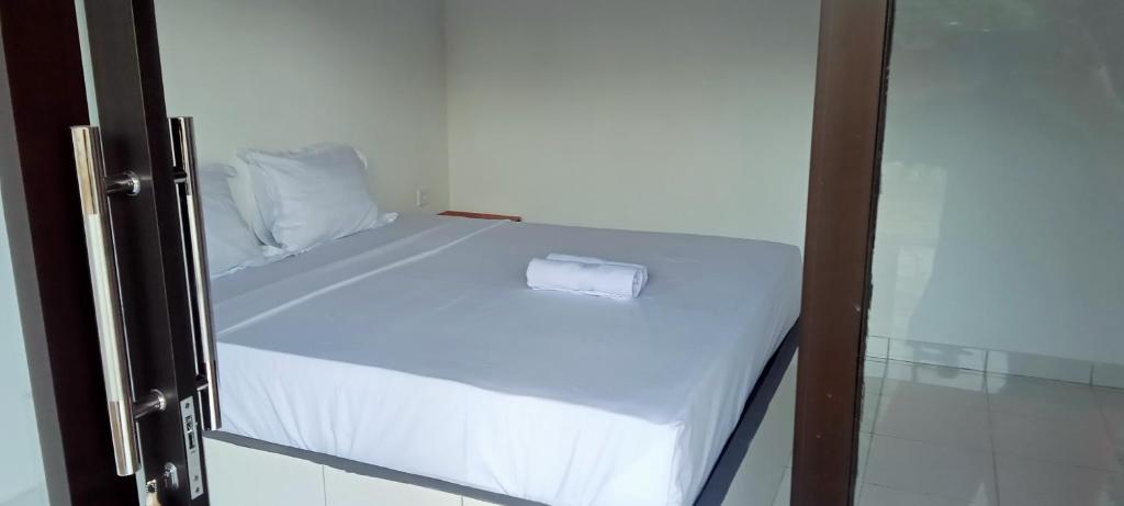 uma pequena cama branca com uma toalha em Giri Homestay em Amed