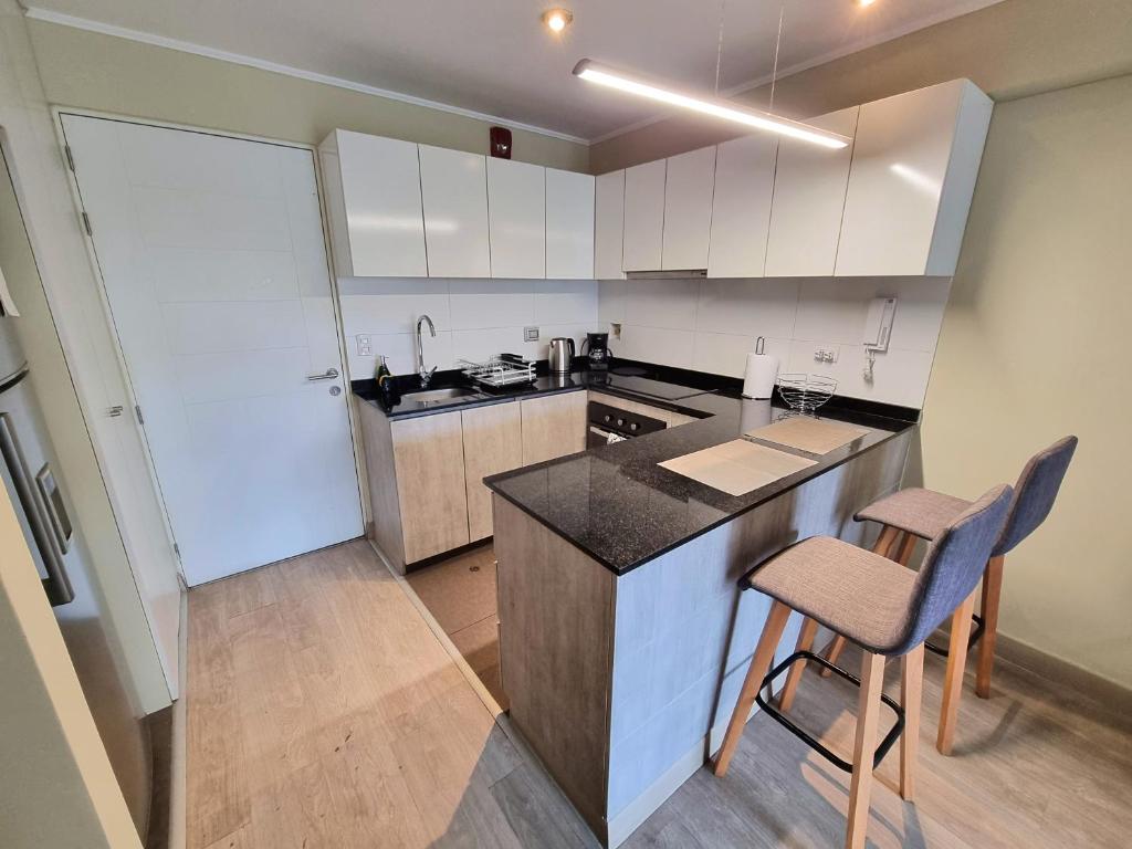 a kitchen with white cabinets and a counter and chairs at Hermoso y céntrico 1BR en Barranco con cochera wifi y netflix in Lima