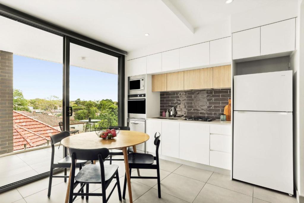 a kitchen with white cabinets and a table and chairs at Modern 2BD in Trendy Inner West in Sydney