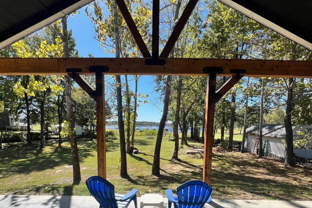 - deux chaises bleues assises sur une terrasse couverte donnant sur les arbres dans l'établissement *NEW* Breathtaking Lakeside #1 Home, à Porum