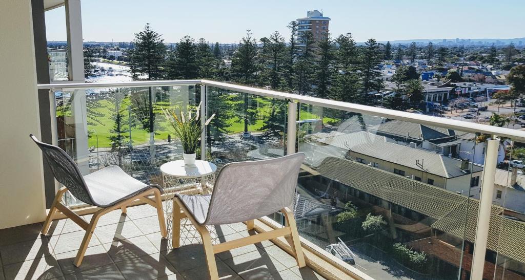 un balcón con 2 sillas y una mesa. en CityViews @ Glenelg * Pool/Beach * Free Parking *, en Glenelg