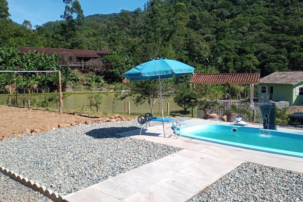 een zwembad met een parasol naast een huis bij Chácara em Luis Alves in Luís Alves