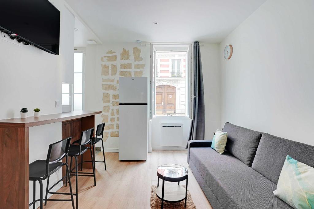 un salon avec un canapé et une cuisine dans l'établissement Peaceful apartment - 1BR 4P - Levallois-Perret, à Levallois-Perret