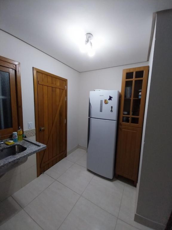 een keuken met een witte koelkast en een houten deur bij Duplex novo in Tramandaí