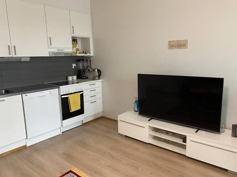 una cocina con una gran TV de pantalla plana en una encimera en Cozy apartment in Rastila, en Helsinki