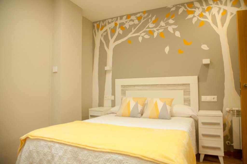 um quarto com uma cama com árvores pintadas na parede em Cumbres de los Picos Apartamento Los Abedules em Poo de Cabrales