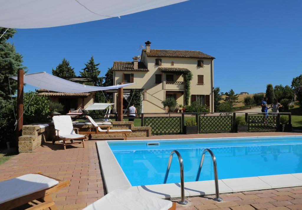 a swimming pool with a house in the background at Country House Binnella in Cingoli