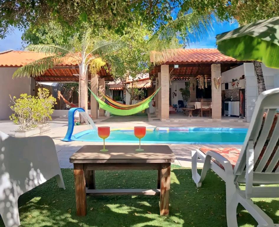 a table with two glasses on it next to a pool at Casa linda na Praia do Francês! Caribe Alagoano in Marechal Deodoro