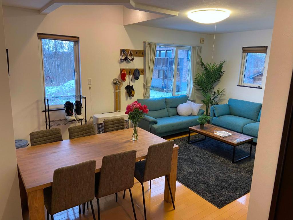 a living room with a table and a blue couch at Yotei Chalets in Niseko