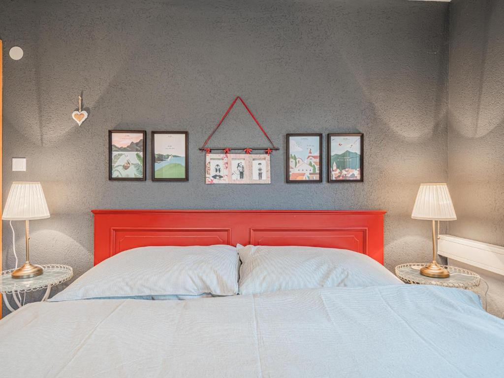 a bedroom with a red bed with four pictures on the wall at Panoramahaus Itter in Itter