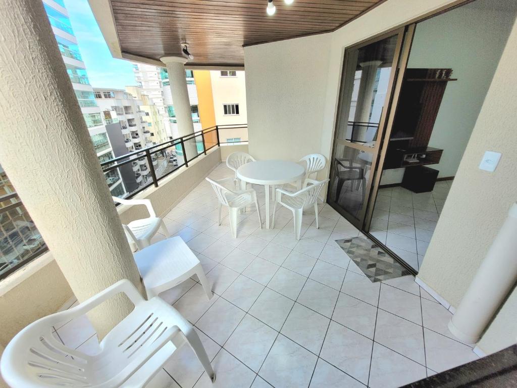 einen Balkon mit einem Tisch und Stühlen auf einem Gebäude in der Unterkunft Apartamento 200 metros da praia 03 quartos com ar condicionado - Meia Praia - Itapema in Itapema