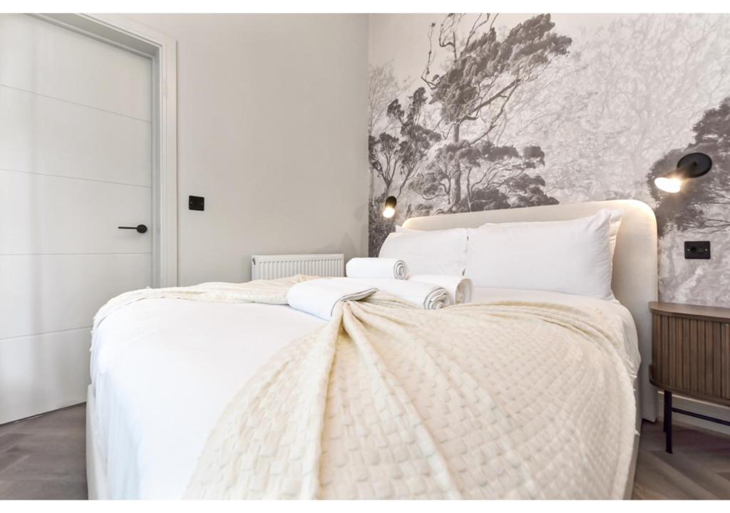 1 dormitorio con 1 cama blanca grande con sábanas blancas en Charming 1BR Oasis in the Heart of Clapton Common en Londres
