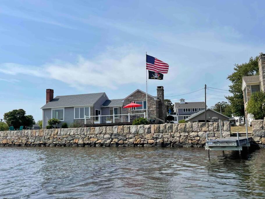 a house on the water with an american flag at Salt Pond Sunrise View & 5 min to beach, sleeps 7 in Charlestown