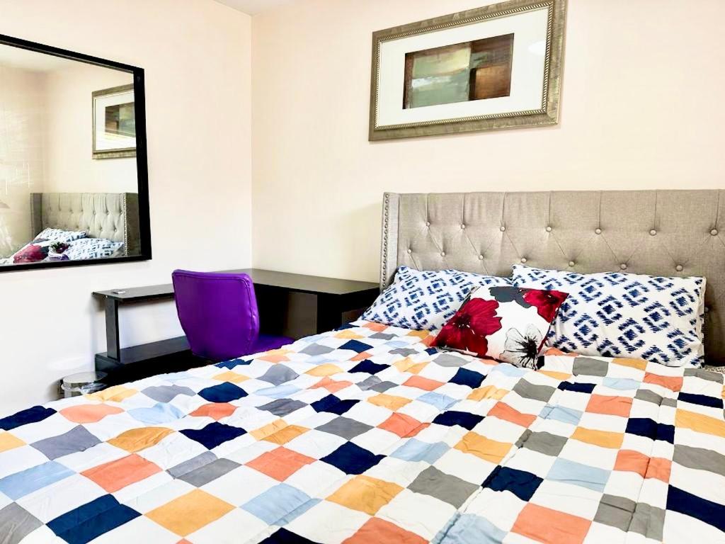 a bedroom with a bed with a colorful quilt at Main floor Room with Queen Bed, Free Parking and Free wi-fi and shared washroom near Fairview Park Mall (Room 2) in Kitchener