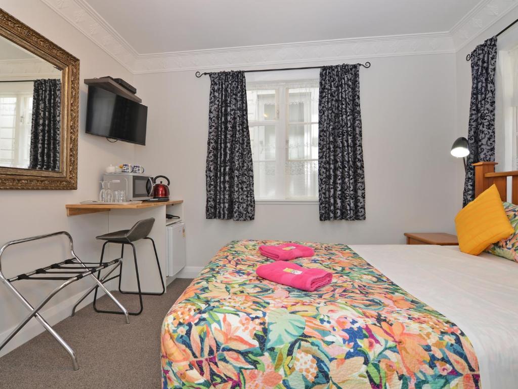 ein Schlafzimmer mit einem Bett, einem Tisch und einem Stuhl in der Unterkunft Richmond Guest House in Wellington