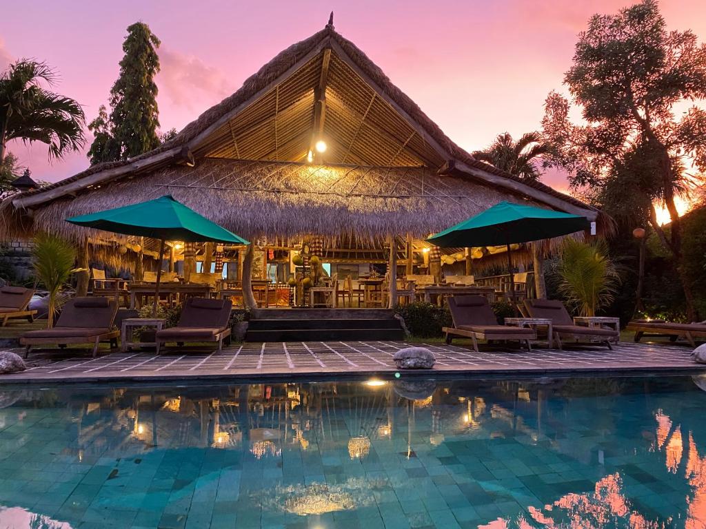 un complexe avec une piscine en face d'un bâtiment dans l'établissement Flower Bud Bungalow Balangan, à Jimbaran