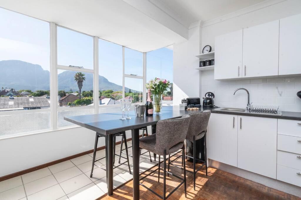 kuchnia ze stołem i krzesłami oraz oknem w obiekcie Apartment with stunning views of Table Mountain w Kapsztadzie
