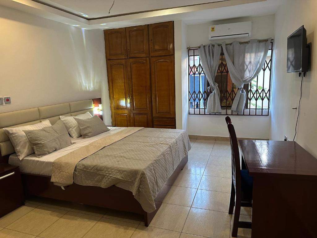 Schlafzimmer mit einem Bett, einem Tisch und einem Fenster in der Unterkunft D Barfi Guesthouse, excellent location in Kumasi
