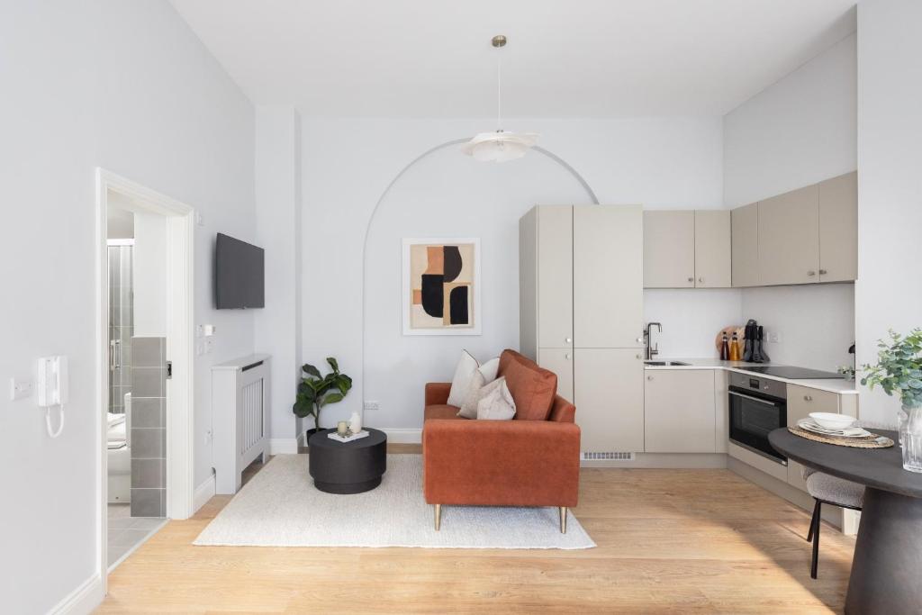 a living room with a chair and a kitchen at Urban Rest Merrion Square Apartments in Dublin