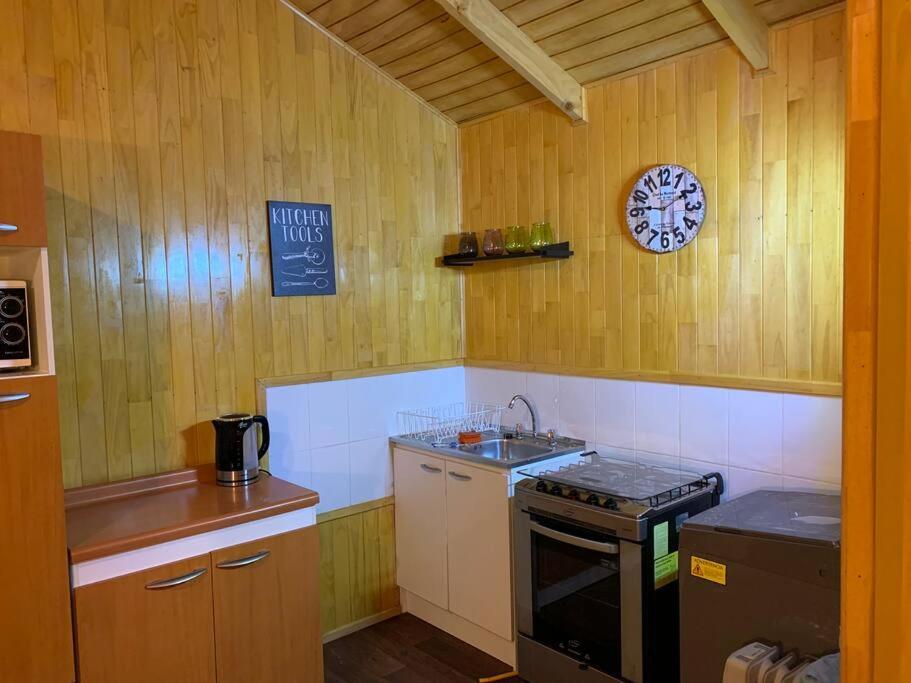 cocina con fogones y reloj en la pared en Cabaña Cardinal, en Puerto Varas