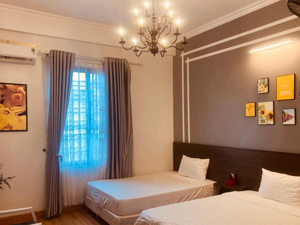 1 Schlafzimmer mit 2 Betten und einem Fenster mit einem Kronleuchter in der Unterkunft Mộc Hương Hotel in Phú Thọ