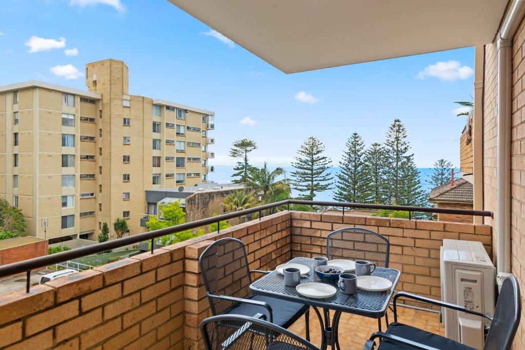 a patio with a table and chairs on a balcony at Sea Vista Escape - A Charming Waterside Stay in Wollongong