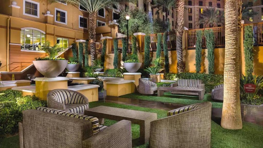 un cortile con sedie, tavoli e palme di Las Vegas! Mediterranean Style Vacation Retreat a Las Vegas
