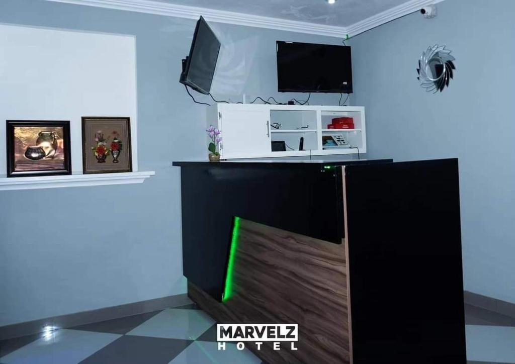a room with a tv and a blue wall at Marvelz Hotel 