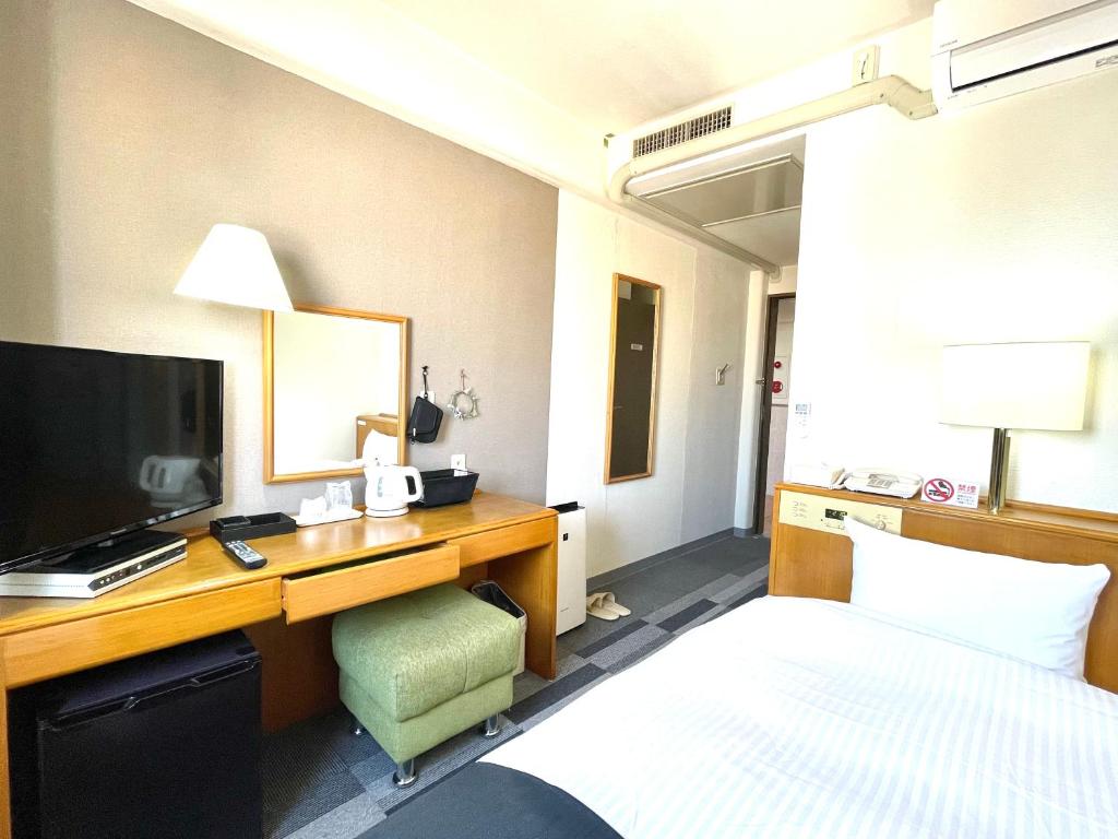 a hotel room with a bed and a desk with a television at Aomori Green Park Hotel in Aomori