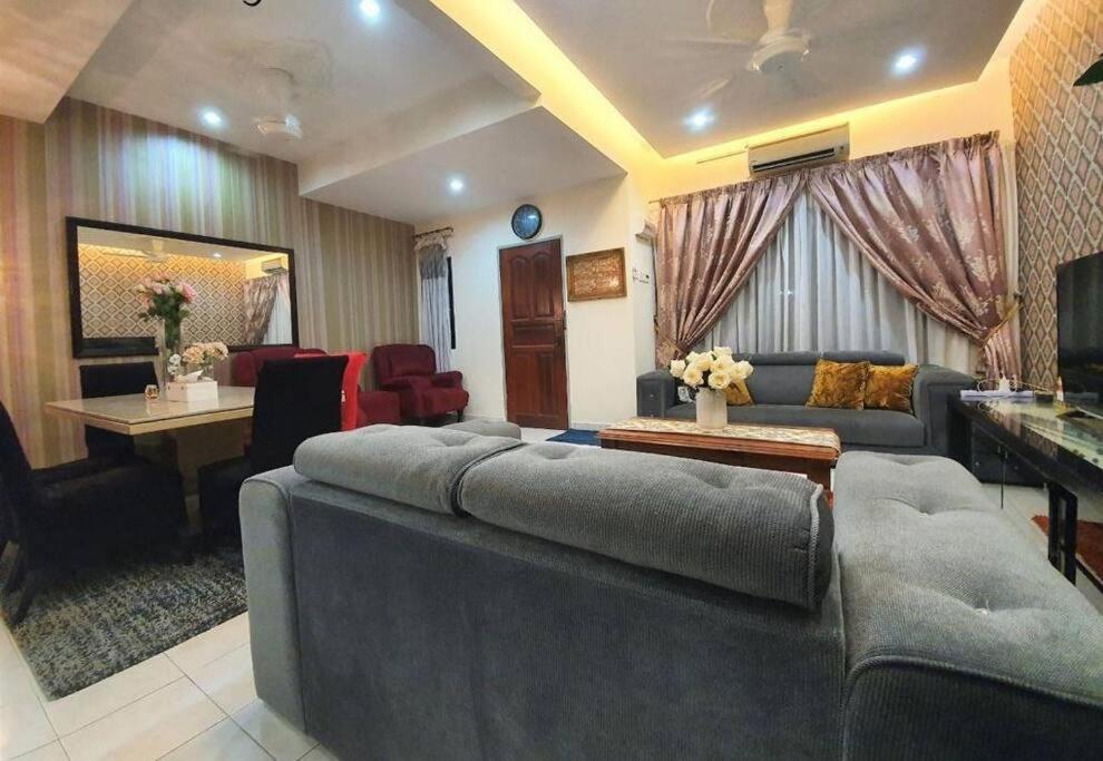 uma sala de estar com um sofá grande e uma mesa em HANI MAWADDAH HOMESTAY SEKSYEN 7 SHAH ALAM em Shah Alam