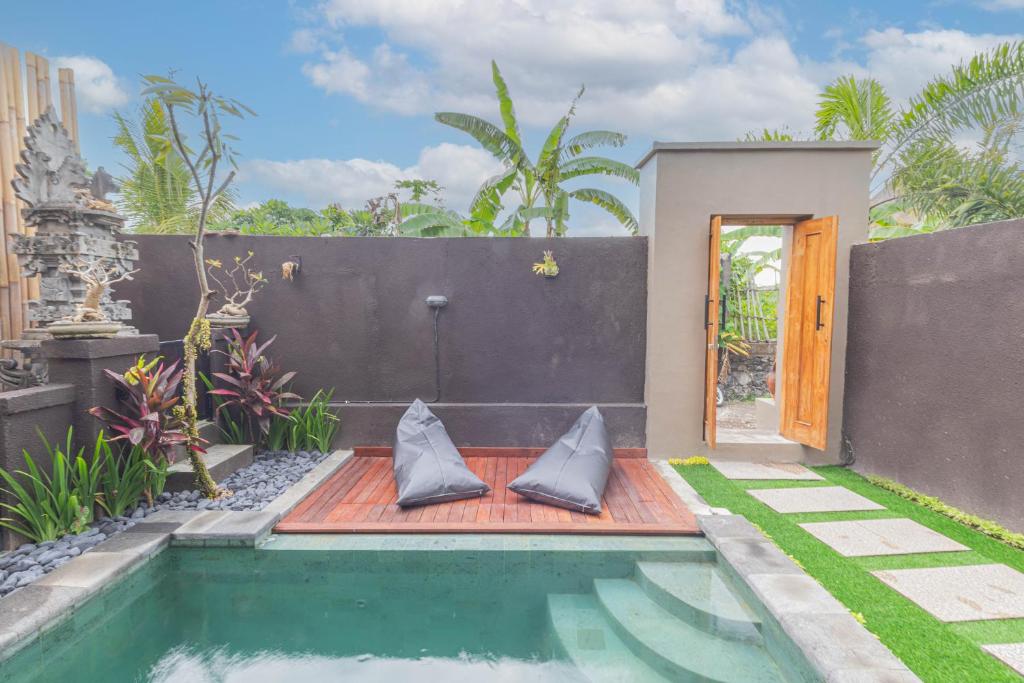 a swimming pool in a garden with a house at Sekar Bali Homestay in Gianyar