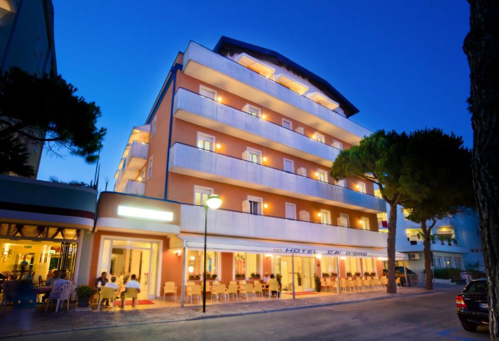 a building with people sitting outside of it at night at Hotel Ca' D'Oro in Caorle